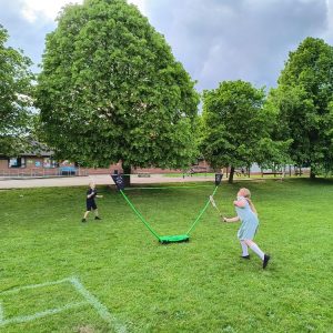 Children playing Badminton using a Sure Shot Quick Fit Set and rackets on a school playing field