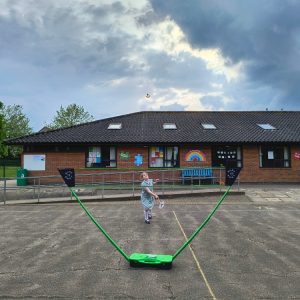 Child playing Badminton using a Sure Shot Quick Fit Set and rackets on a primary school sports court playground