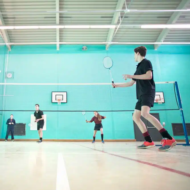 Students playing badminton in a sports hall