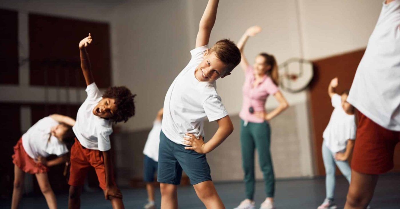 Children exercising in a sports hall during a PE lesson