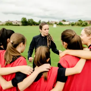 All girls team huddled around their coach