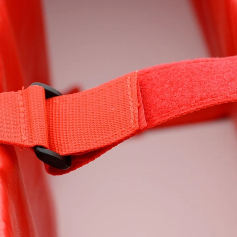 Close-up of a vibrant red fabric strap attached to a red plastic surface with a black buckle. The image conveys a sense of boldness and durability.