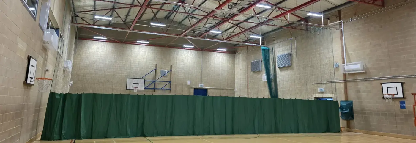 A sports hall with a green curtain pulled accross