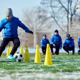 Boy playing football on an icy pitch